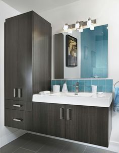 a bathroom with blue and white tile on the walls, cabinets, and sink in it