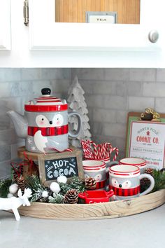 a tray filled with coffee mugs and christmas decorations