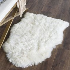 a white sheepskin rug sitting on top of a wooden floor next to a chair