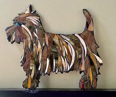 a wooden sculpture of a dog made out of strips of wood and glass, on a shelf