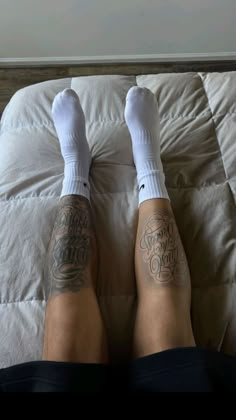 a person with tattoos on their legs laying on a bed