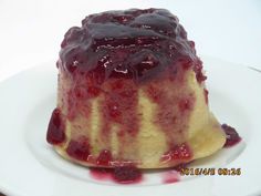 a white plate topped with a cake covered in blueberry sauce