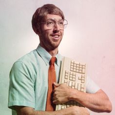 a man wearing glasses holding a computer keyboard