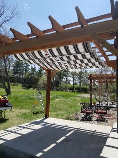 an outdoor patio with tables and chairs under a striped awning over the picnic area