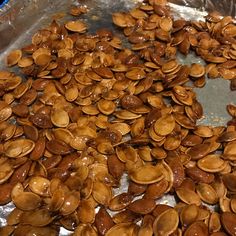 a pile of sunflower seeds sitting on top of a metal pan covered in brown liquid