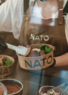 a person wearing an apron and holding a bowl with food in it