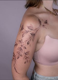 a woman wearing a bra with flowers on her arm and chest tattooing it's upper half