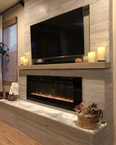 a living room with a fireplace and television mounted on the wall next to a potted plant