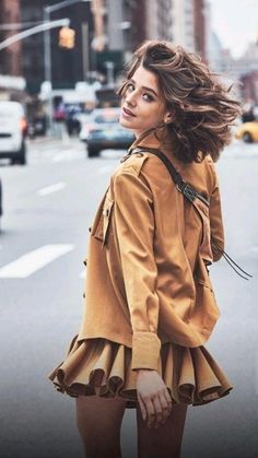 a woman standing in the middle of a street with her hair blowing in the wind