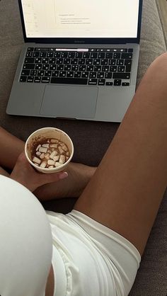 a person sitting on a couch with their legs crossed and holding a bowl of food