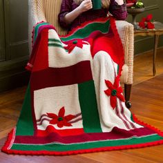 a woman sitting in a chair with a blanket on her lap and holding a book