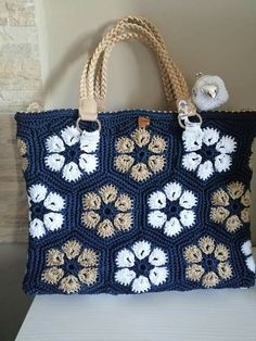 a blue crocheted bag sitting on top of a white table next to a wall