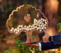 a man in a suit is holding a plaque with flowers on it and pointing to the tree