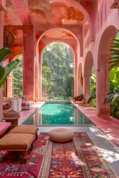 an indoor swimming pool in the middle of a room with pink walls and arches on either side