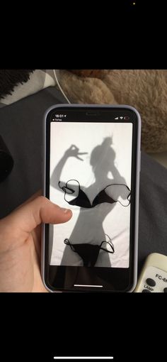 someone is holding up their cell phone to take a photo with her shadow on the screen