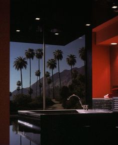 palm trees are reflected in the window of a modern bathroom with an outdoor jacuzzi tub