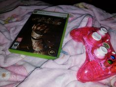 a video game sitting on top of a pink blanket next to a nintendo wii controller