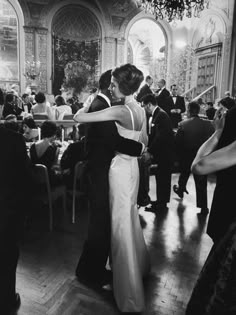 black and white photograph of two people dancing at a formal event with other people in the background