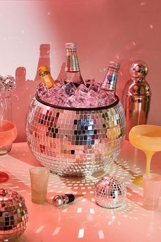 a disco ball filled with lots of bottles and glasses on top of a pink table