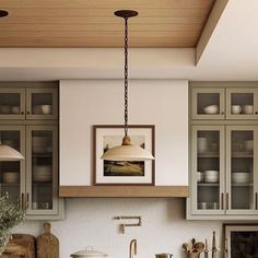 an image of a kitchen setting with green cabinets and white counter tops, hanging light over the sink