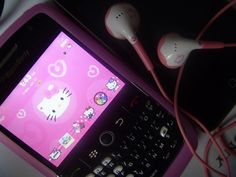 a pink cell phone with hello kitty on the screen and earphones attached to it