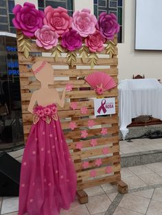 a woman standing in front of a wooden sign with paper flowers on it's side