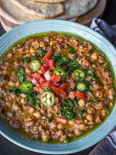 a blue bowl filled with beans and veggies next to some pita bread