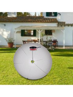 a large white umbrella sitting on top of a lush green field next to a house