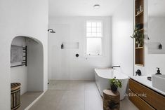 a bathroom with a tub, sink and mirror in it's center wall is shown