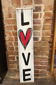 a wooden sign that says i love with a red heart on it in front of a brick wall