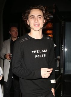 a young man wearing a black sweatshirt with the words the last poets printed on it