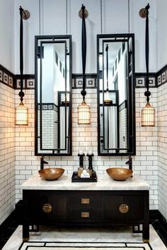 a bathroom with two sinks, mirrors and lights on the wall above them is black and white tile