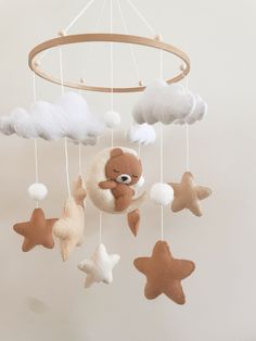 a teddy bear is hanging from a mobile with clouds and stars in the shape of animals