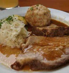 a white plate topped with meat and gravy covered in gravy next to mashed potatoes