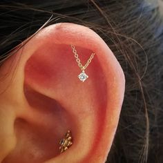 a woman's ear with a single diamond on it