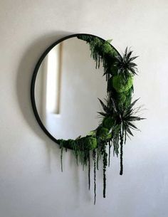 a circular mirror with plants hanging on it