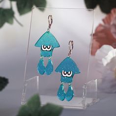 Introducing our stunning Swimming Squid Acrylic Earrings, inspired by the vibrant world of Splatoon! These delightful dangle earrings feature a unique jelly shimmer finish that adds a playful touch to any outfit. Lightweight and comfortable, they are perfect for everyday wear or a fun day out. Whether you're a fan of swimming in ink or simply love eye-catching accessories, these earrings will make a splash in your jewelry collection. Treat yourself or surprise a friend with these enchanting earr Whimsical Blue Earrings For Party, Quirky Dangle Earrings For Party, Fun Blue Drop Earrings, Quirky Hypoallergenic Dangle Earrings, Quirky Drop Earrings With Ear Wire, Quirky Handmade Dangle Earrings, Handmade Quirky Drop Earrings, Fun Blue Dangle Earrings, Blue Handmade Novelty Earrings