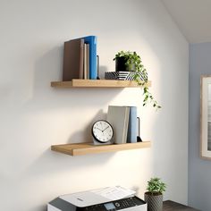 two wooden shelves with books on them and a clock mounted to the wall next to each other