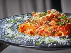 a blue plate topped with pasta covered in sauce and parmesan cheese