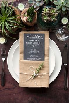 a place setting with napkins, silverware and succulents