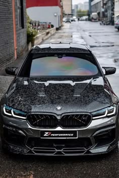 a black car parked in front of a brick building on a wet street with no one around