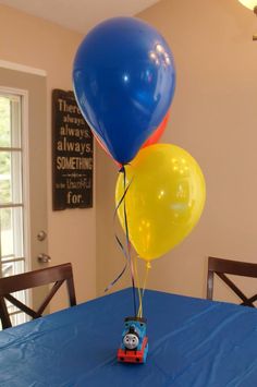 a thomas the tank engine balloon sitting on top of a blue tablecloth covered table