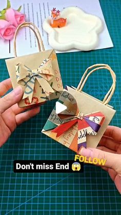 two hands holding small paper bags on top of a table