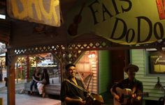 two men are playing guitars in front of a store with the words fas do do written on it