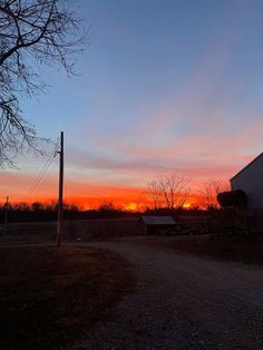 the sun is setting over an old barn