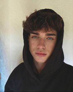 a young man wearing a black hoodie and looking at the camera with an intense look on his face