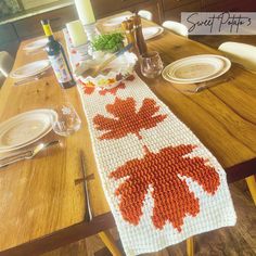 a crocheted table runner with an orange maple leaf on it sits on a wooden dining room table