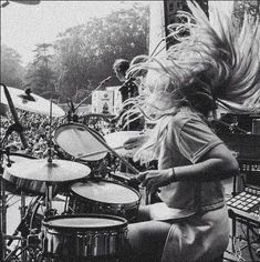 a woman with her hair blowing in the wind while playing drums at a music festival