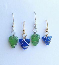 three different colored glass hearts hanging from gold earwires on white background with blue and green beads