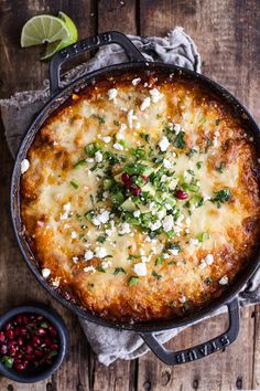 a baked dish with cheese and herbs in a cast iron skillet on a wooden table